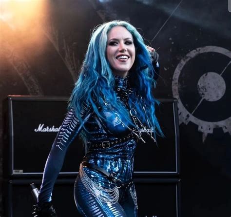 A Woman With Blue Hair Is Performing On Stage