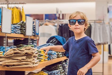 The Boy Tries On Clothes In The Childrens Clothing Store Stock Photo