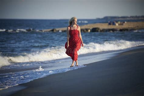 Stunning Young Blonde Woman Poses At Beach In Red Sundress Stock Image