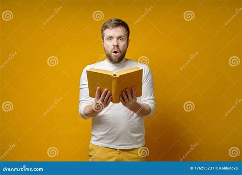 Attractive Man With A Book In Hands Is Fascinated At What He Read And