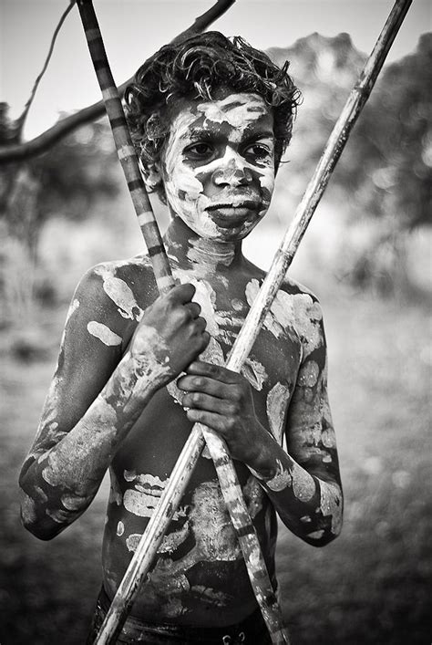 A Man With Paint On His Face Holding Two Sticks