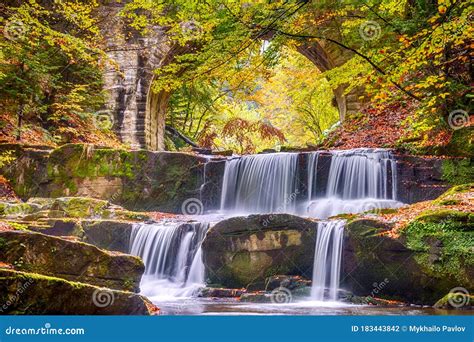 River Waterfall In The Forest And Arch Of A Stone Bridge Stock Photo