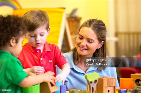 Nursery Teacher Supervising Children Playing With Building Blocks High