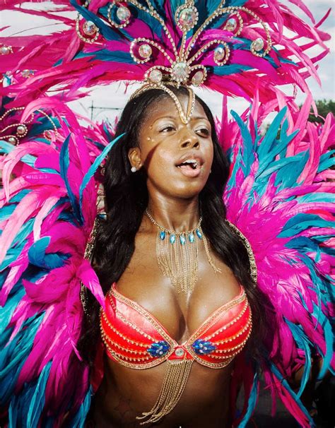 A Woman In Pink And Blue Costume With Feathers On Her Head Posing For The Camera