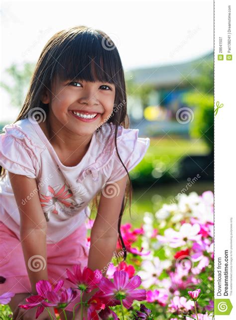 Asian Little Girl Standing With Hands On Knees In A Meadow