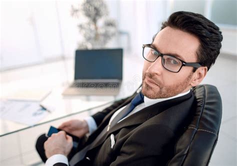 Businessman Sitting At His Desk And Looking At The Camera Stock Photo