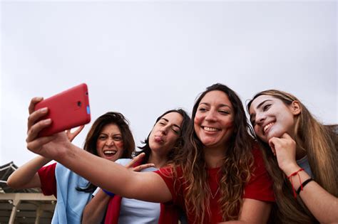 group of female soccer fans taking selfies of themselves wearing team jerseys women taking