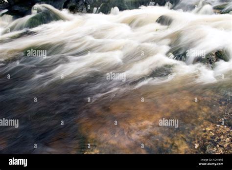 A Slow Shutter Speed Of River Water Flowing Over The Rocks Giving The