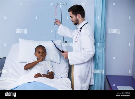 Doctor Adjusting Iv Drip While Patient Lying On Bed Stock Photo Alamy