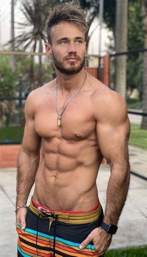 A Shirtless Man With No Shirt Standing In Front Of A Fence