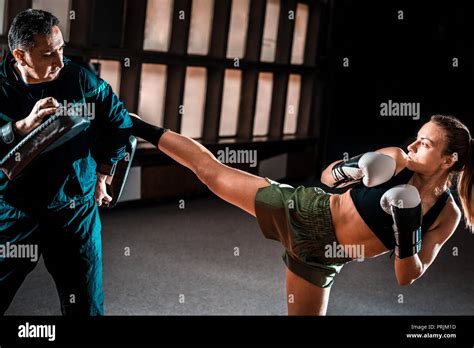 Young Adult Woman Doing High Kick During Kickboxing Training Exercise