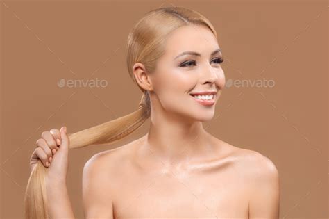 Beautiful Nude Blonde Woman Holding Her Long Hair Isolated On Brown