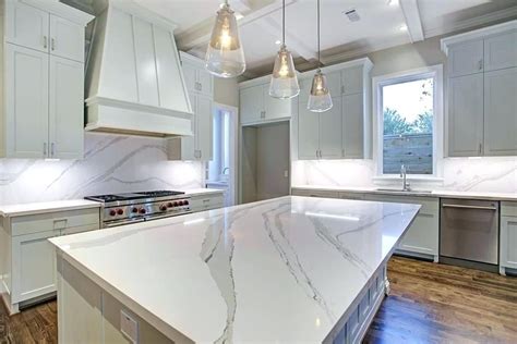 A Large Kitchen With Marble Counter Tops And White Cabinets Along With