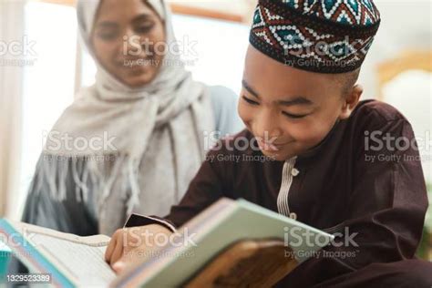 Shot Of A Young Muslim Mother And Her Son Reading In The Lounge At Home