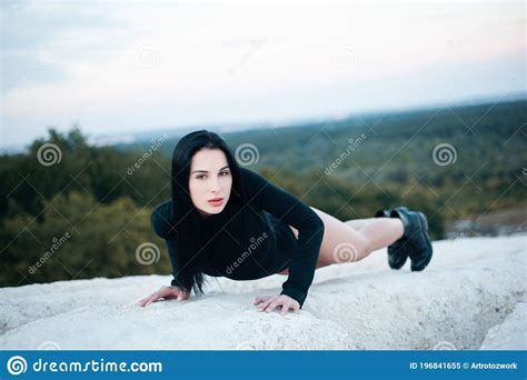 Slender Brunette In A Black Bodysuit Posing In Nature Lying On A Chalk