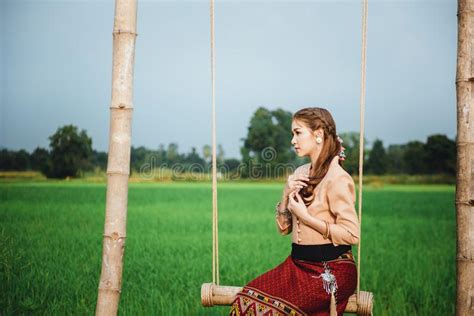 Beautiful Asian Woman In Local Dress Sitting On Swing And Enjoy Natural On Bamboo Bridge Stock