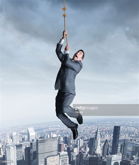 Businessman Hanging On To Fraying Rope Above City High Res Stock Photo