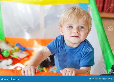 Cute Little Baby Boy Playing In Colorful Playpen Indoors Stock Image
