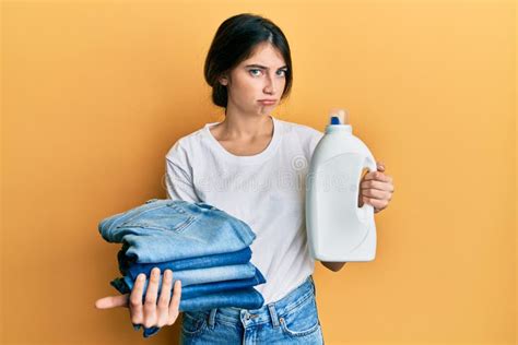 Young Caucasian Woman Doing Laundry Holding Detergent Bottle And Folded