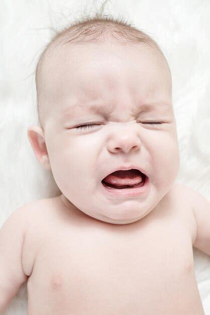 Premium Photo Crying Baby Lies On A White Fluffy Background