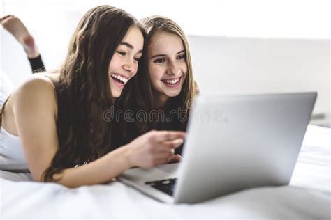 Teen Girls Lying On Bed Using A Laptop Stock Photo Image Of