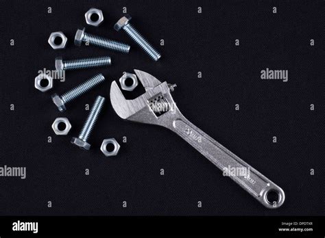 Adjustable Wrench With Screws And Nuts On Black Background Stock Photo