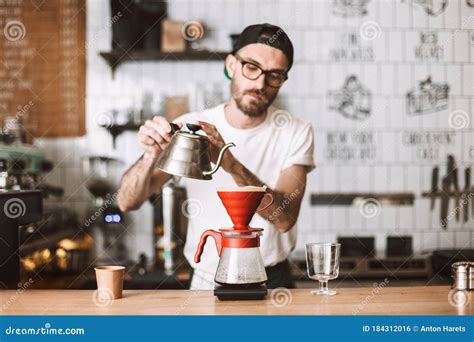 Barista In Eyeglasses And Cap Standing At Counter And Preparing Pour