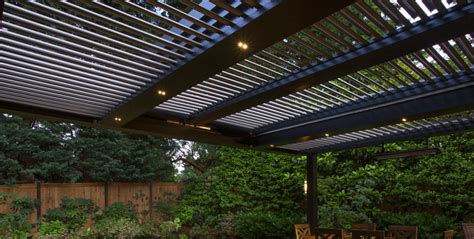 An Outdoor Dining Area Is Lit Up By Lights And Surrounded By Greenery