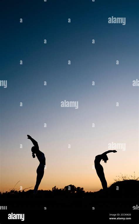 Women Bending Over Backwards While Practicing Yoga Outdoors Stock Photo