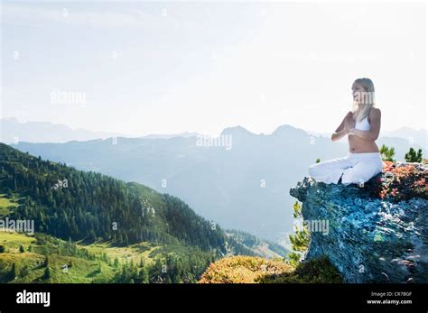 Austria Salzburg County Young Woman Sitting On Rock And Doing