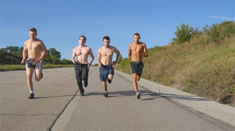 group of runners men jogging at highway male sport athletes training outdoor at summer stock