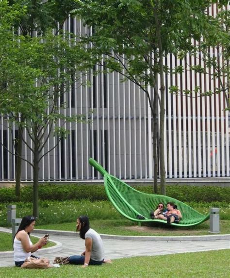 two women sitting on the ground in front of a green hammock and trees