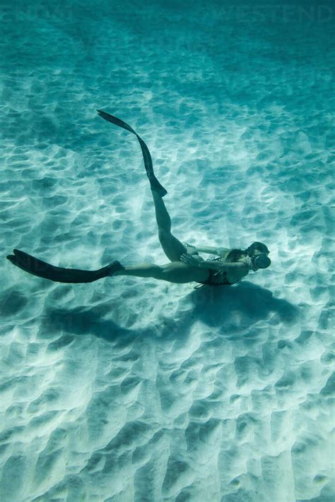 Side View Of Slim Female In Swimsuit And Flippers Swimming Underwater
