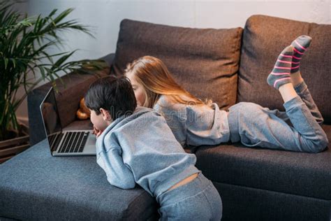Mädchen Und Junge Der Laptop Verwendet Und Auf Sofa Liegt Stockbild Bild Von