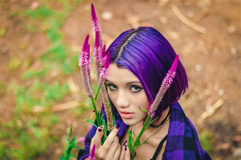 Photo Of Purple Haired Woman In Purple And Black Plaid Collared Shirt Next To Purple Flowers