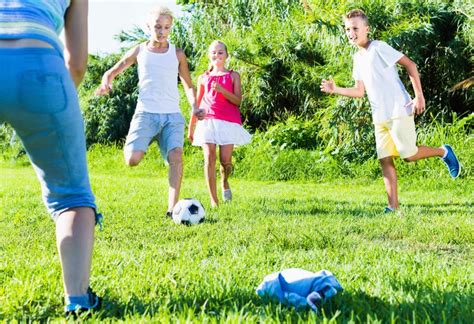 Three Happy Kids Playing With Ball Outdoors Running Together Stock