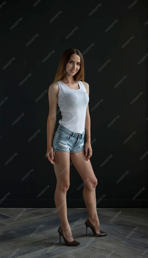 Premium Photo Young Woman In A White Tank Top And Denim Shorts On A