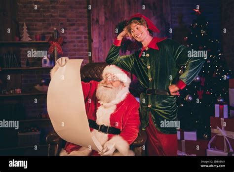 Photo Portrait Of Santa Claus And Elf Reading Nice And Naughty List