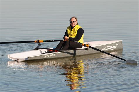 A Man Sitting On Top Of A Kayak In The Middle Of The Water With Oars