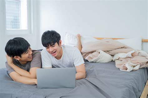 Young Cute Asian Gay Couple Looking And Using Laptop On