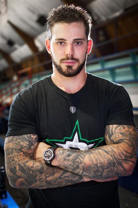 A Man With His Arms Crossed Wearing A Black T Shirt And Green Star Tattoo