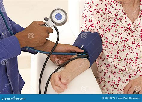 Doctor Taking Blood Pressure To An Elderly Patient At Home Stock Photo