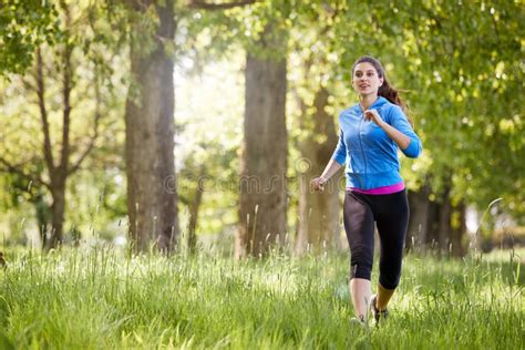 Young Woman Exercising Running Through Countryside Field Stock Photo