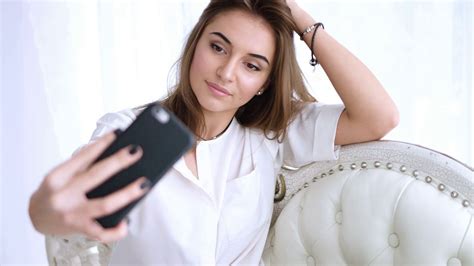 Young Girl Taking A Selfie Sitting On The Sofa Young Brunette Girl Takes Photograph Of Herself