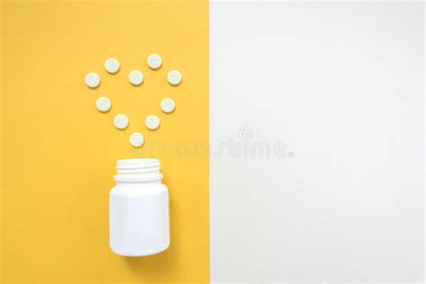 medication bottle and white pills spilled on yellow pastel colored background medication and