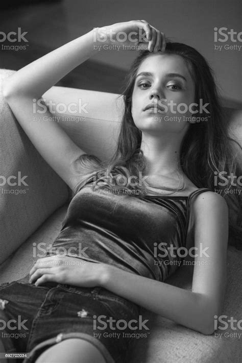 Girl Wearing Jeans Shorts Sitting On Sofa Stock Photo Download Image
