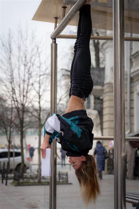 Girl Hanging By Feet Upside Down In The Street And Reading Book