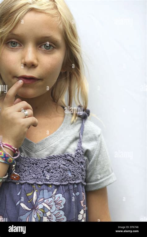 A Young Girl With Blonde Hair And Blue Eyes Her Hand To Her Mouth
