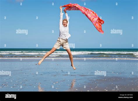 New Zealand Mature Woman Jumping At Ninety Mile Beach Stock Photo Alamy
