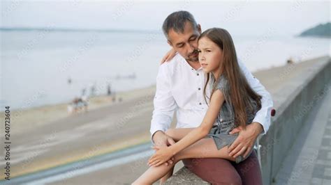 A Girl Sits On Her Father S Lap A Man And His Daughter Are Sitting On